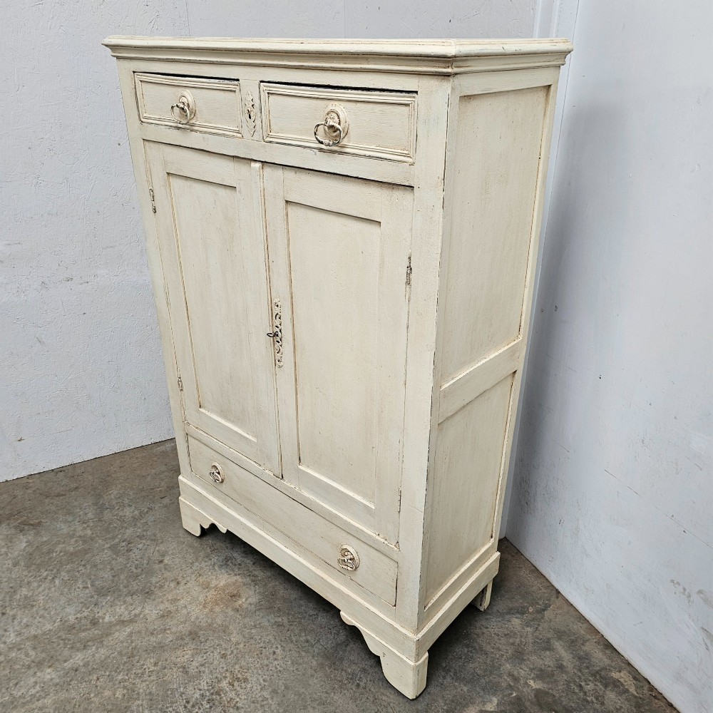 A small off-white painted French linen cupboard featuring two upper drawers, two panelled cupboard doors, and a single lower drawer with drop ring handles. View III
