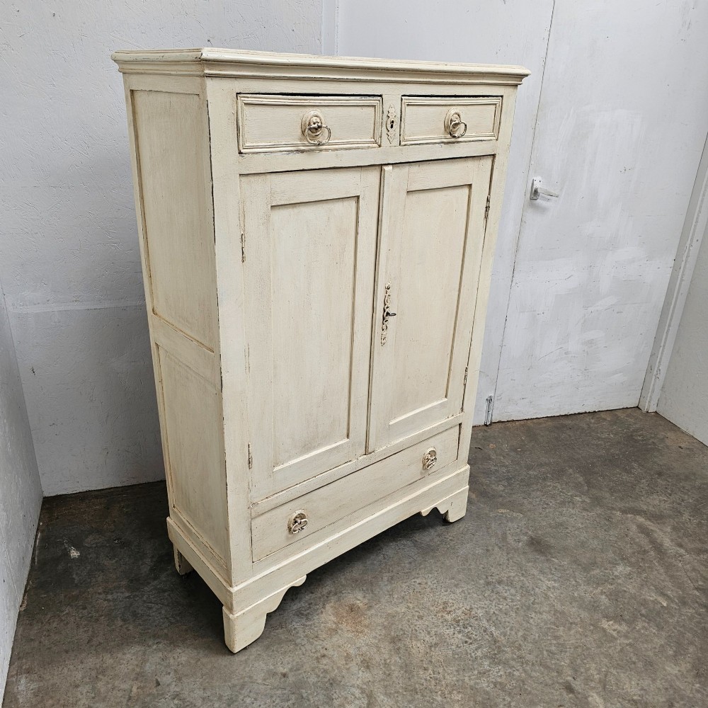 A small off-white painted French linen cupboard featuring two upper drawers, two panelled cupboard doors, and a single lower drawer with drop ring handles. View IV