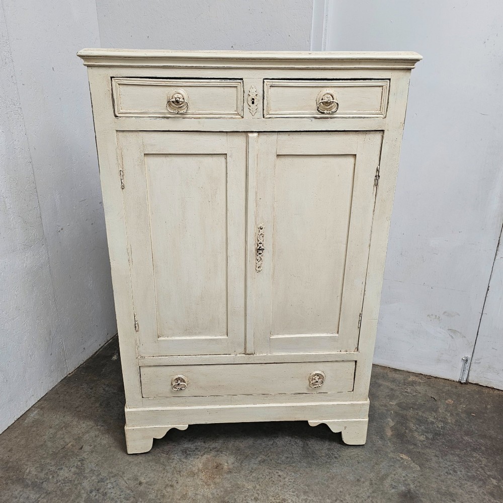 A small off-white painted French linen cupboard featuring two upper drawers, two panelled cupboard doors, and a single lower drawer with drop ring handles.