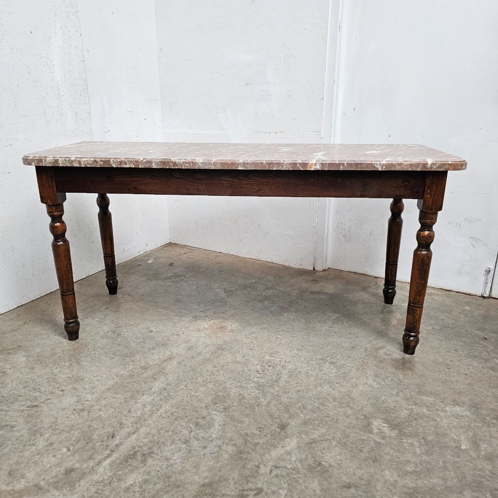 A French patisserie table featuring a thick reddish veined marble top supported by a dark wood frame with four turned legs.