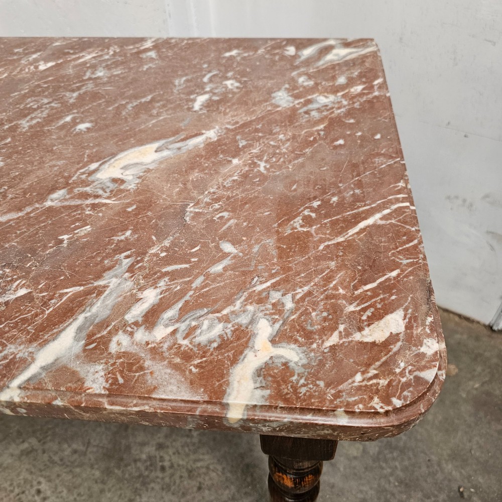A French patisserie table featuring a thick reddish veined marble top supported by a dark wood frame with four turned legs. View V