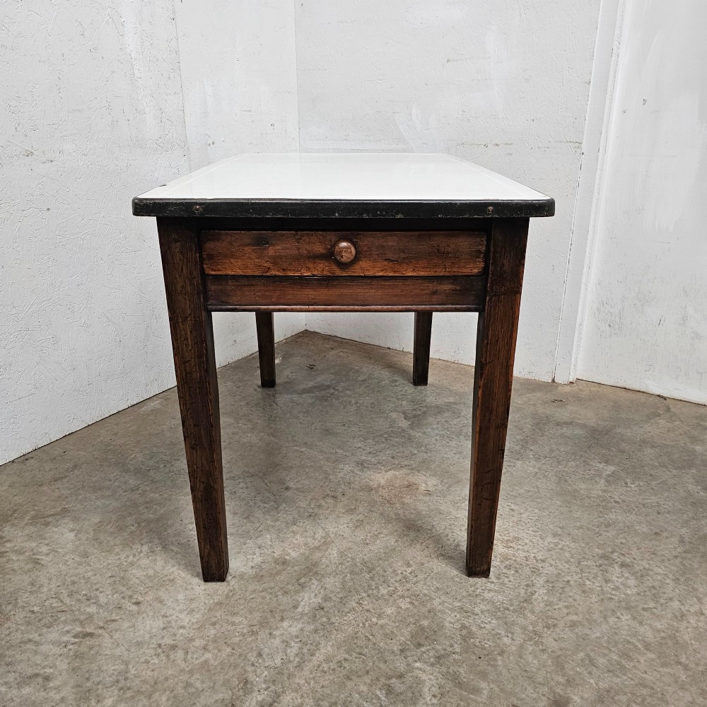 An early 20th-century dark oak kitchen prep table featuring a white vitreous enamel top and a single frieze drawer with a wooden knob. View II