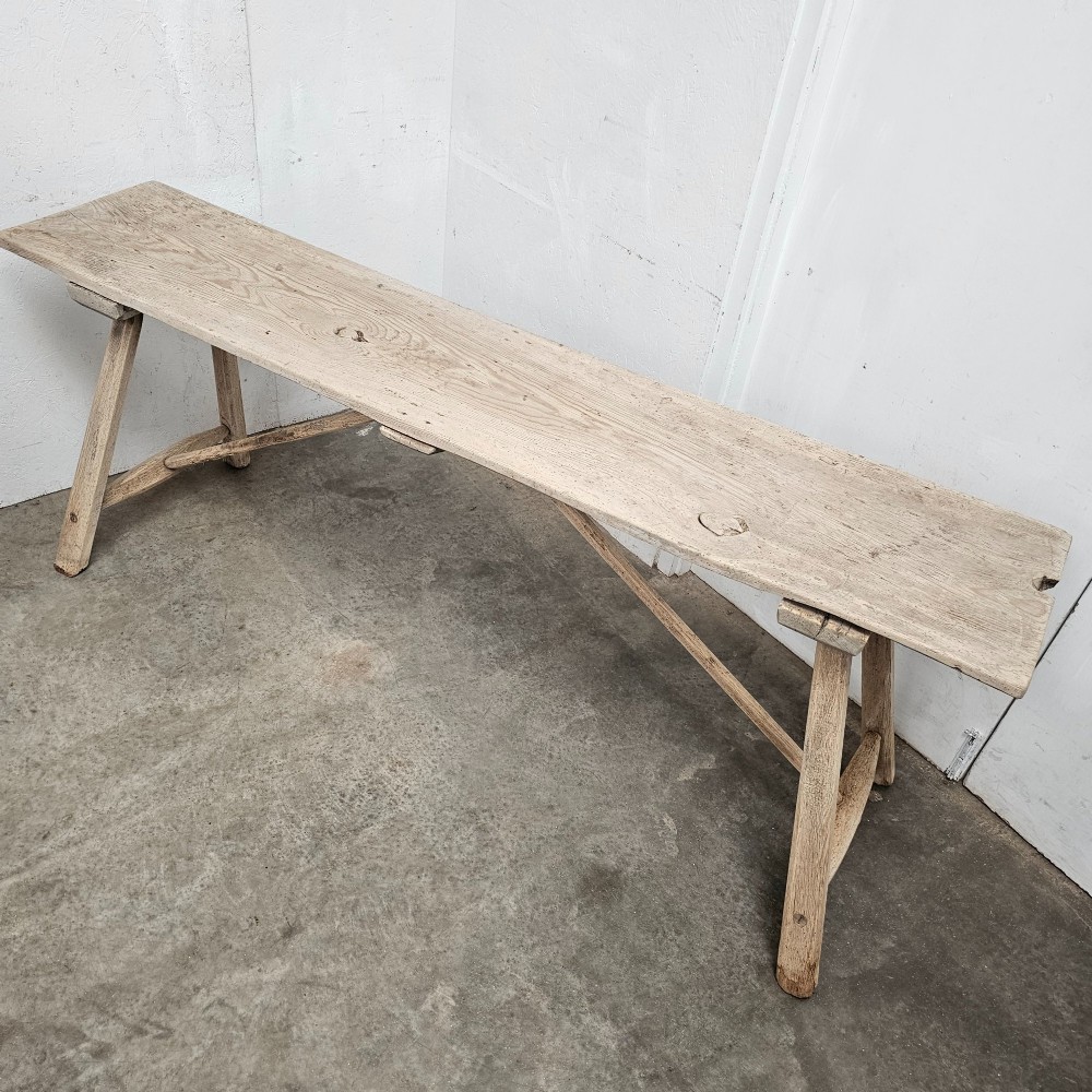A long, narrow antique scrubbed pine console table featuring angled legs with diagonal cross-bracing and an unvarnished timber finish. View III