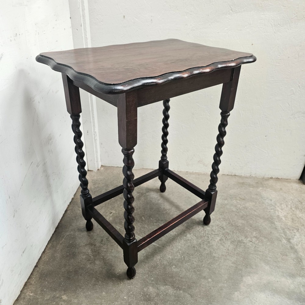 A dark oak side table with a scalloped pie-crust top, four barley-twist turned legs, and a square base stretcher. View II