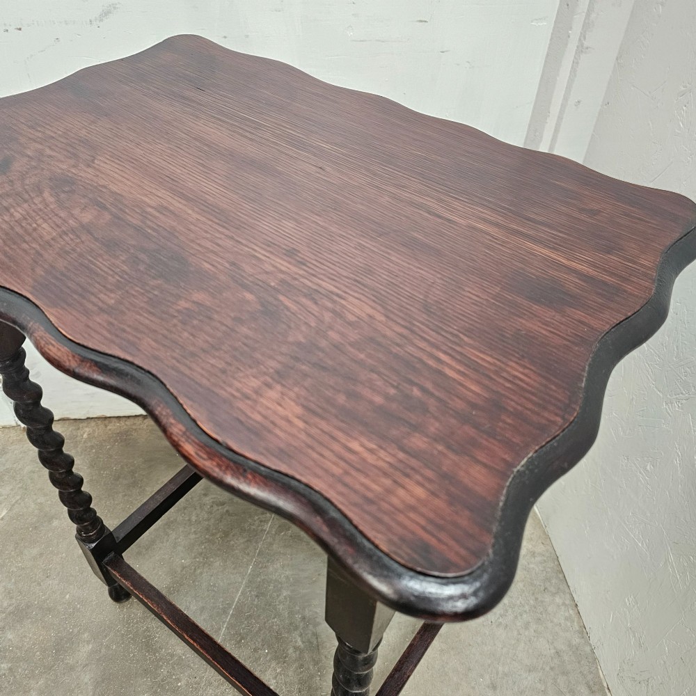 A dark oak side table with a scalloped pie-crust top, four barley-twist turned legs, and a square base stretcher. View III