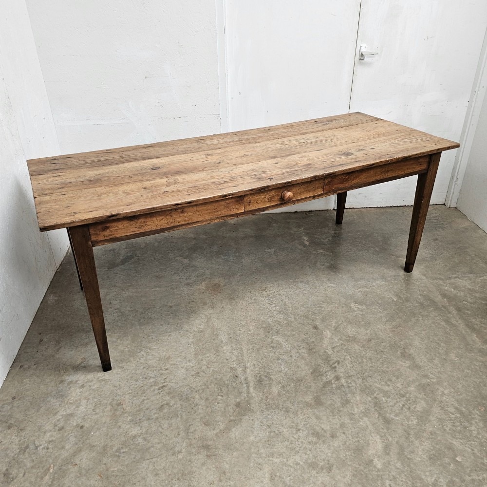 An antique French farmhouse dining table crafted with a planked pine top, oak apron, single frieze drawer with a turned wooden knob, and tapered square legs. View II
