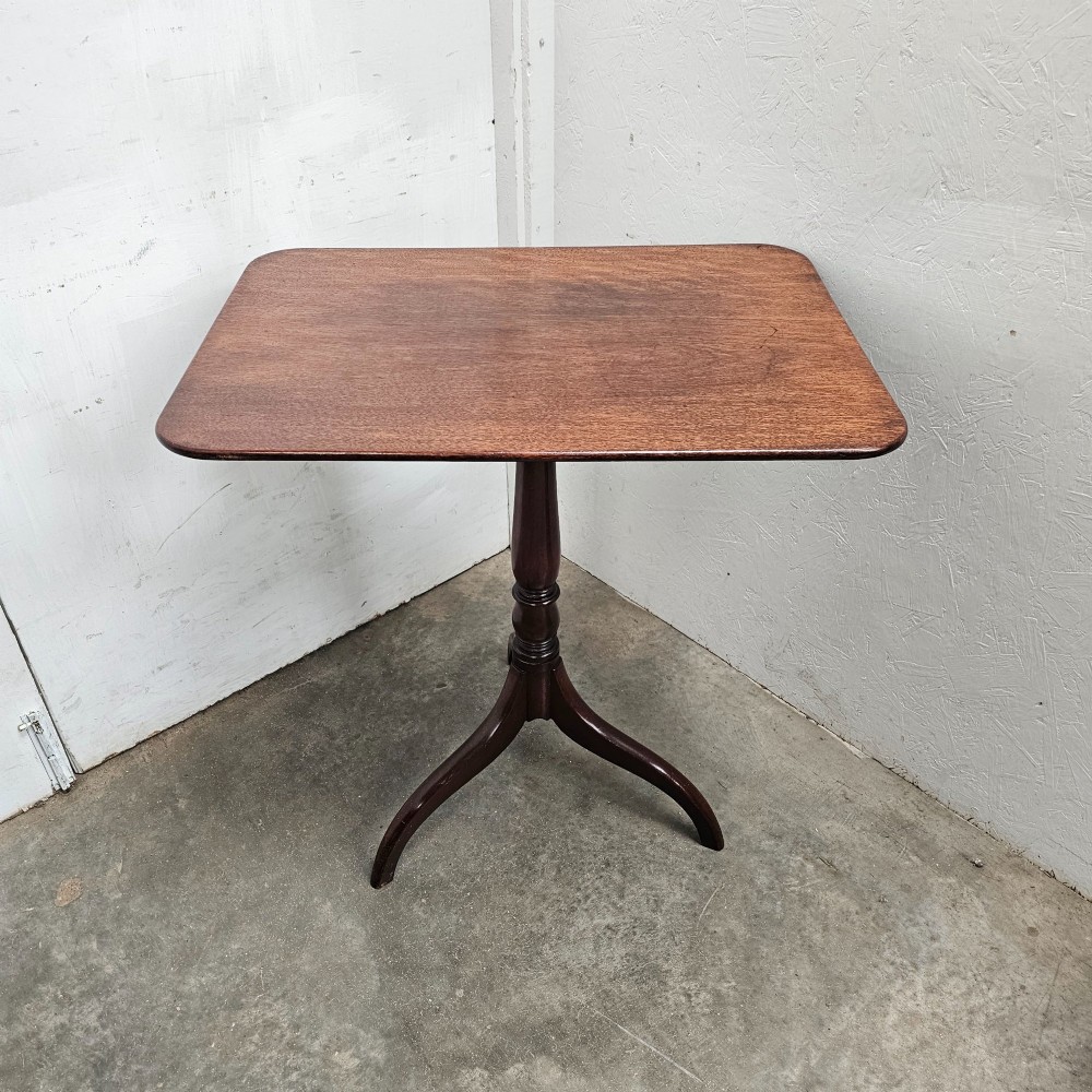 An English mahogany wine table featuring a rounded rectangular top supported by a turned central column and a three-legged tripod base.