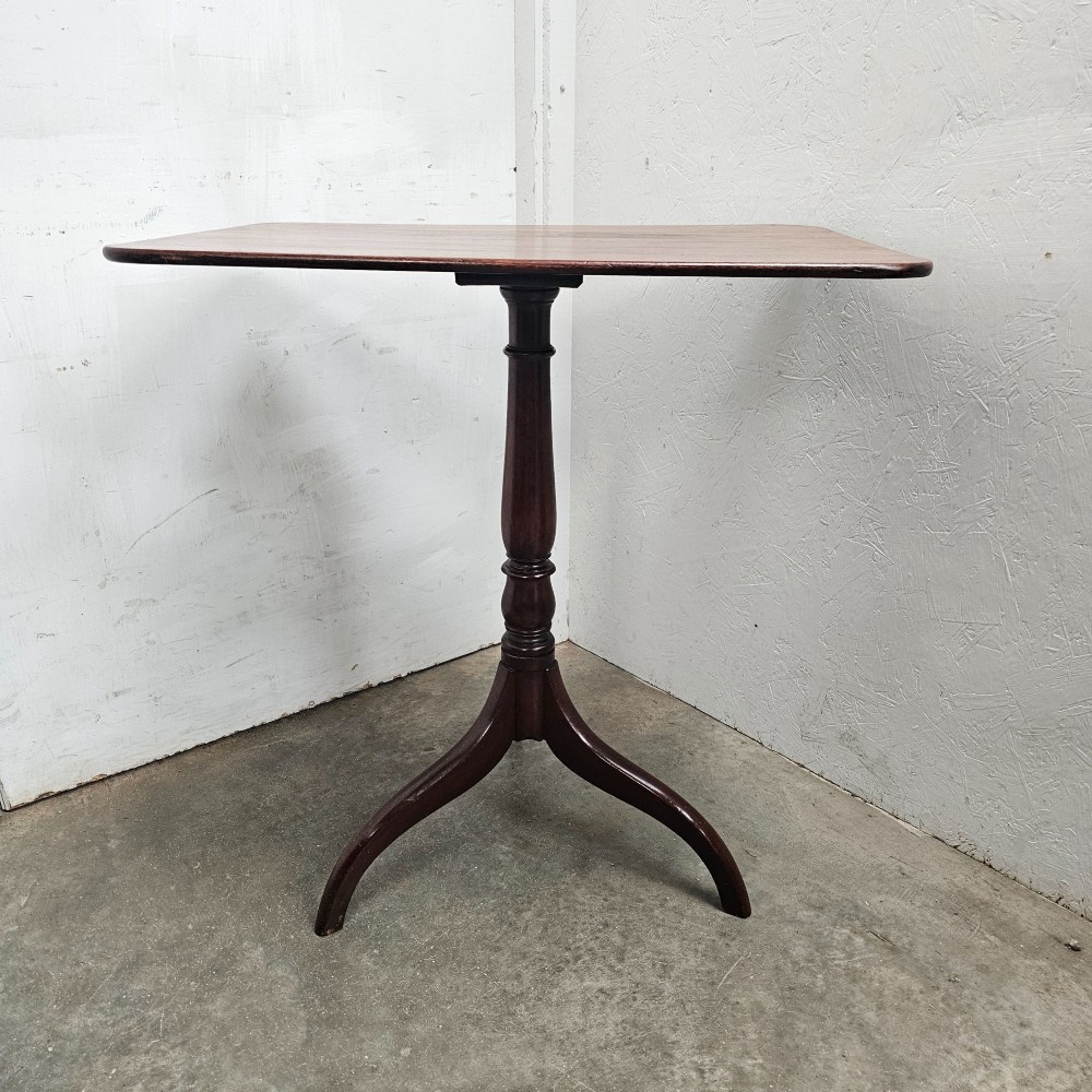An English mahogany wine table featuring a rounded rectangular top supported by a turned central column and a three-legged tripod base. View V