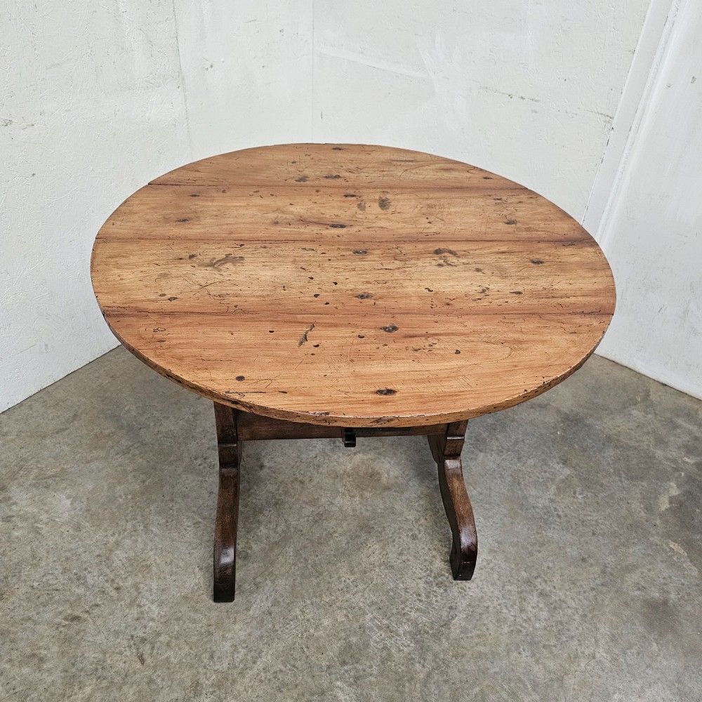 A circular French provincial folding vendange table crafted from oak and cherrywood with a planked surface tilted vertically on a trestle base. View III