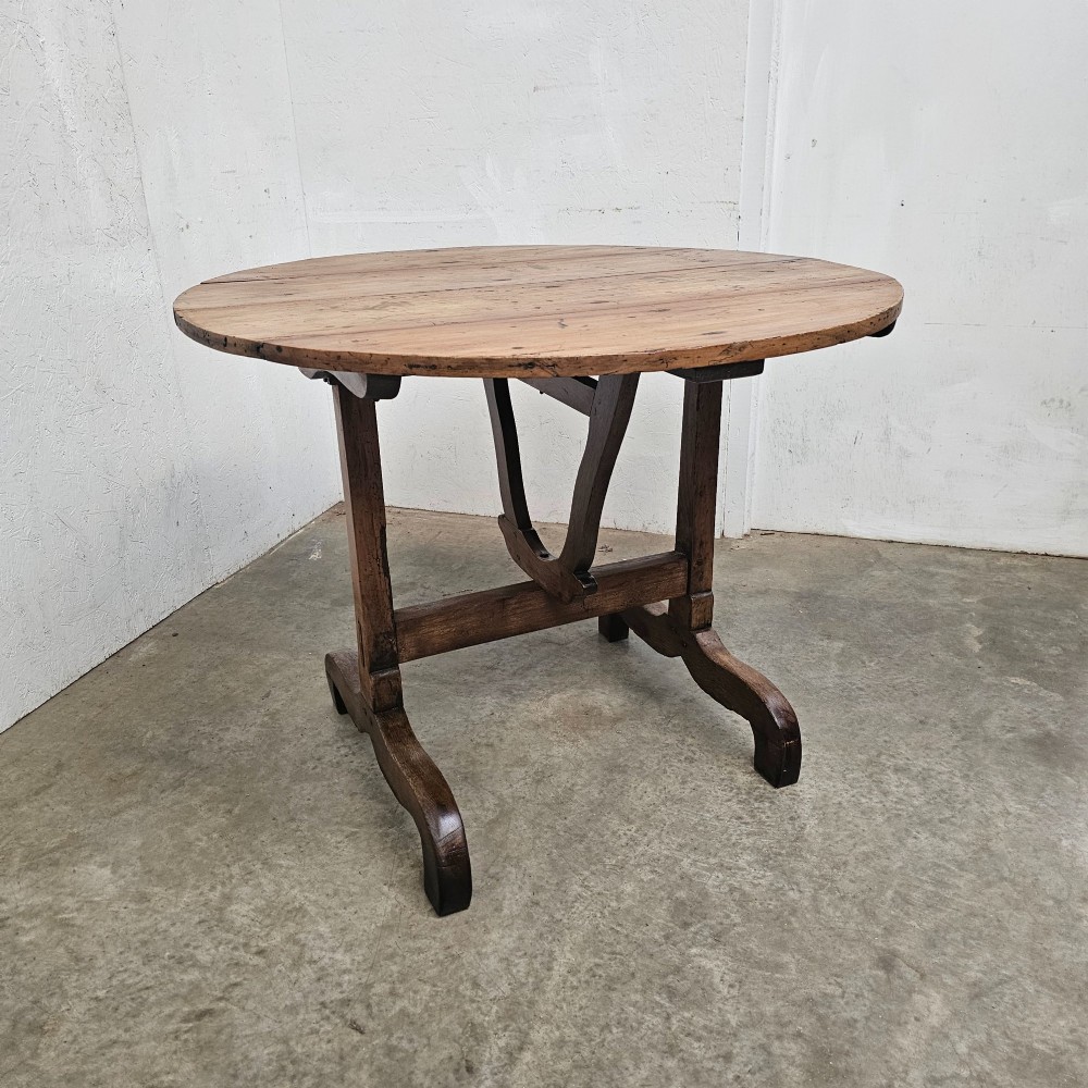 A circular French provincial folding vendange table crafted from oak and cherrywood with a planked surface tilted vertically on a trestle base. View IV