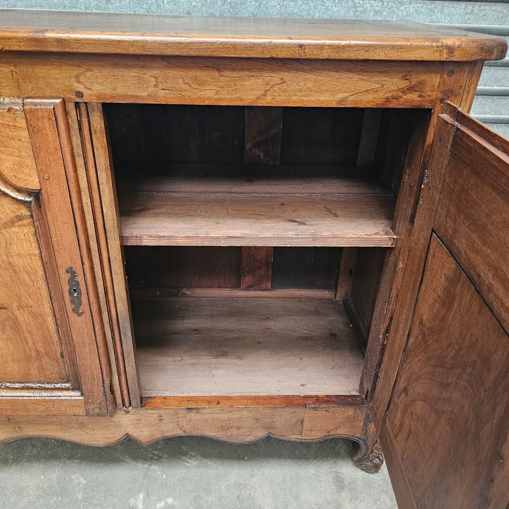 An 18th-century French provincial walnut four-door sideboard featuring hand-carved arched door panels, dark metal escutcheons, and a scalloped lower apron. View III