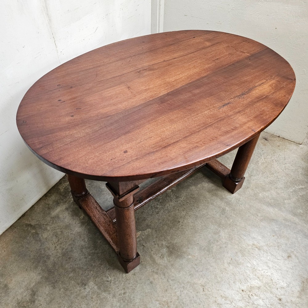 An 18th-century French oval walnut table featuring four turned legs joined by a low H-stretcher. View III
