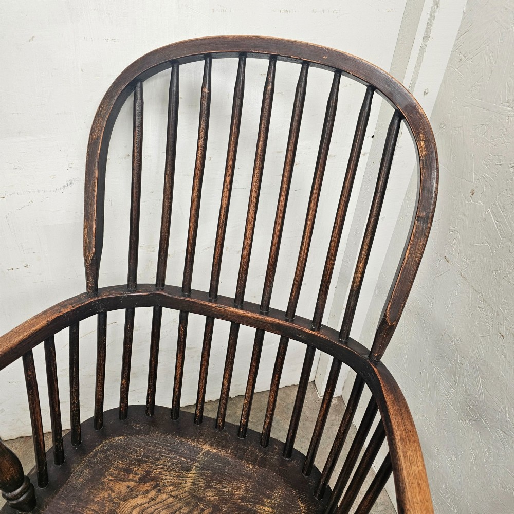 An antique dark brown oak and ash Windsor armchair featuring a high hoop back with vertical spindles, turned legs, and a shaped solid wood seat. View II