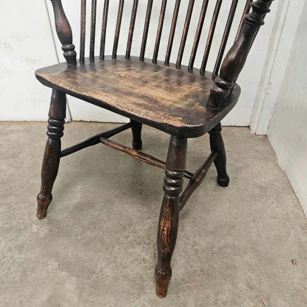 An antique dark brown oak and ash Windsor armchair featuring a high hoop back with vertical spindles, turned legs, and a shaped solid wood seat. View III