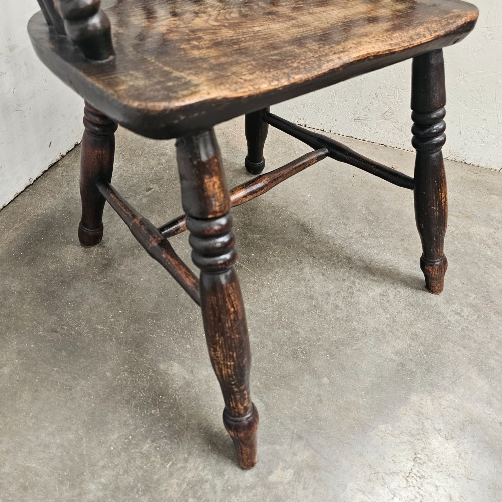 An antique dark brown oak and ash Windsor armchair featuring a high hoop back with vertical spindles, turned legs, and a shaped solid wood seat. View IV