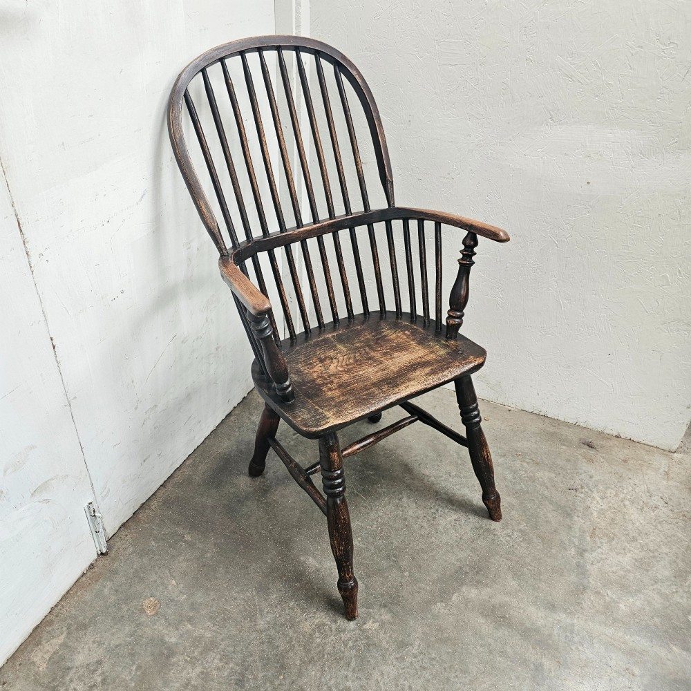 An antique dark brown oak and ash Windsor armchair featuring a high hoop back with vertical spindles, turned legs, and a shaped solid wood seat. View V