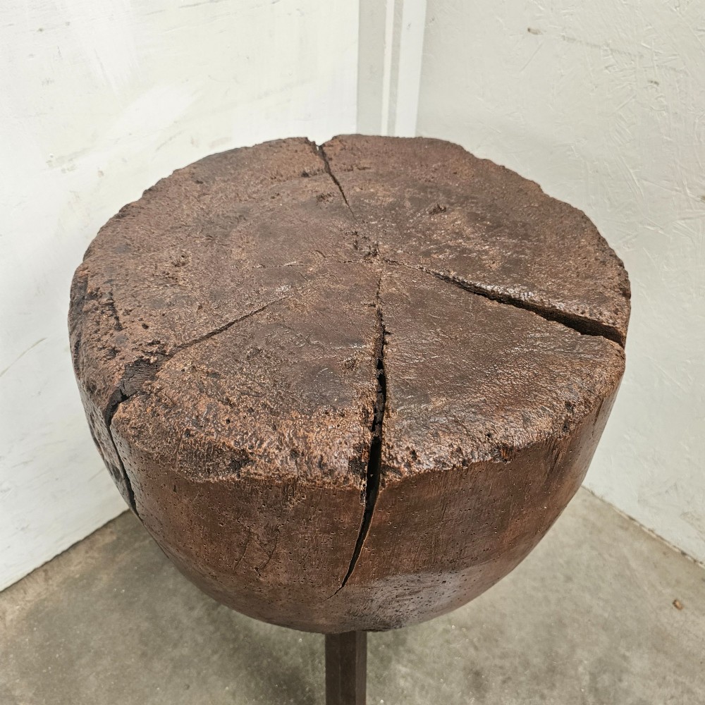 A solid dark brown carved beech timber game block mounted on three splayed wooden legs with natural surface splits. View II