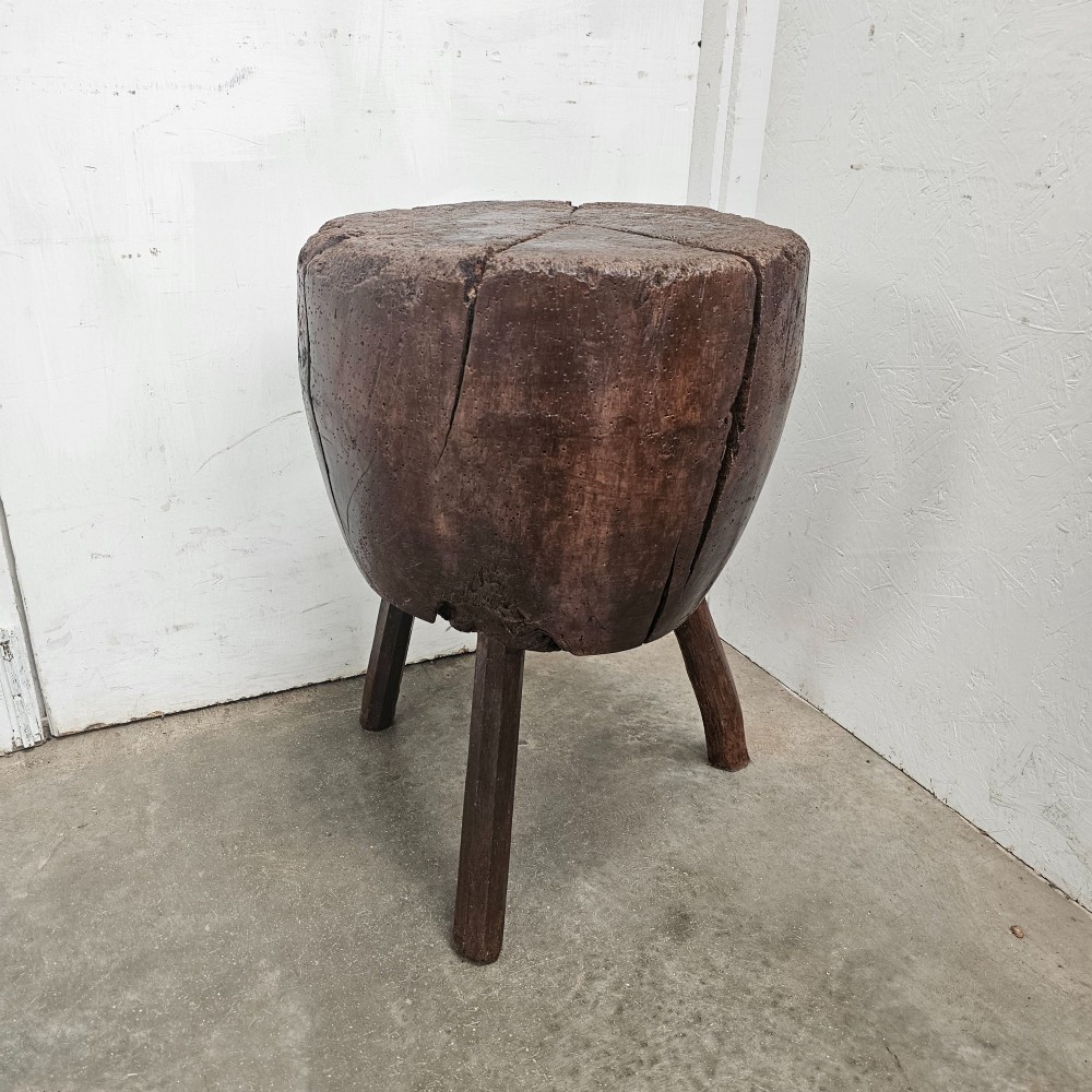 A solid dark brown carved beech timber game block mounted on three splayed wooden legs with natural surface splits. View III