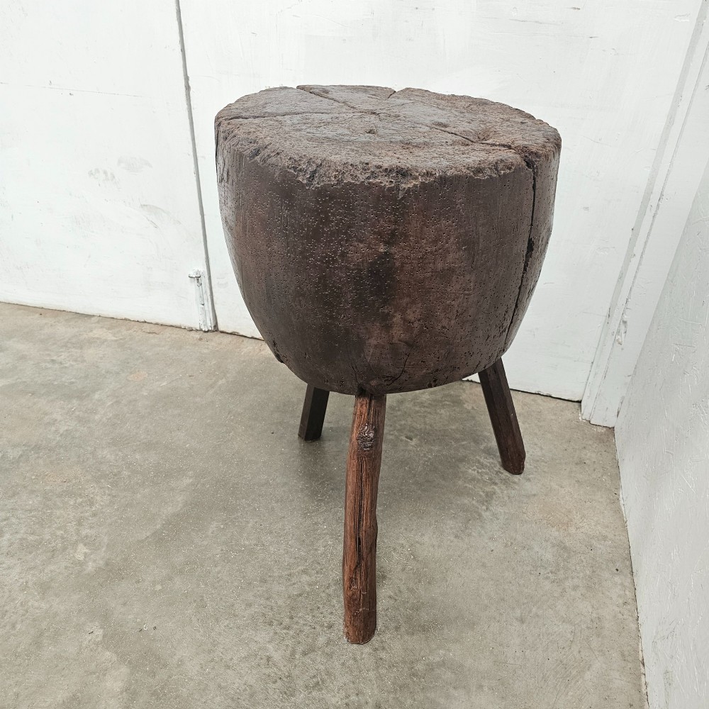 A solid dark brown carved beech timber game block mounted on three splayed wooden legs with natural surface splits. View IV