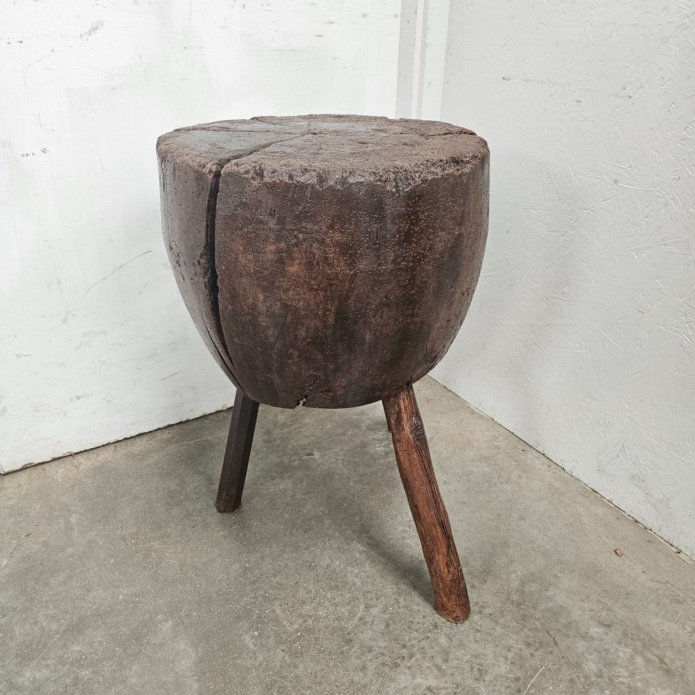 A solid dark brown carved beech timber game block mounted on three splayed wooden legs with natural surface splits. View V