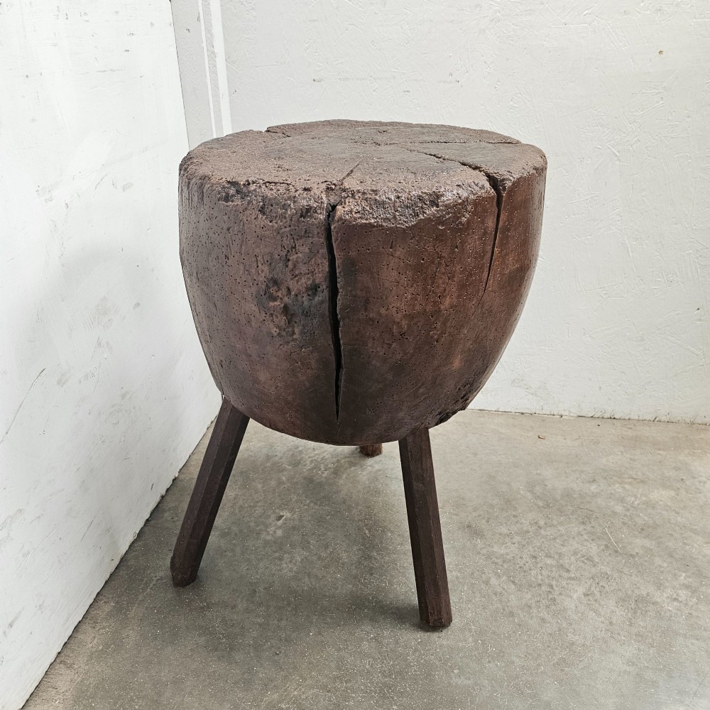 A solid dark brown carved beech timber game block mounted on three splayed wooden legs with natural surface splits. View VI