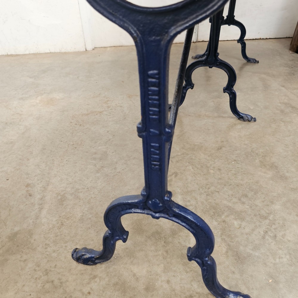 A long rectangular light elm wood table top supported by three curved black iron legs with arching stretchers. View III