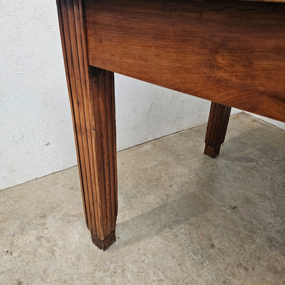 A rectangular French fruitwood dining table featuring a central frieze drawer with a wooden knob and fluted tapered legs. View II