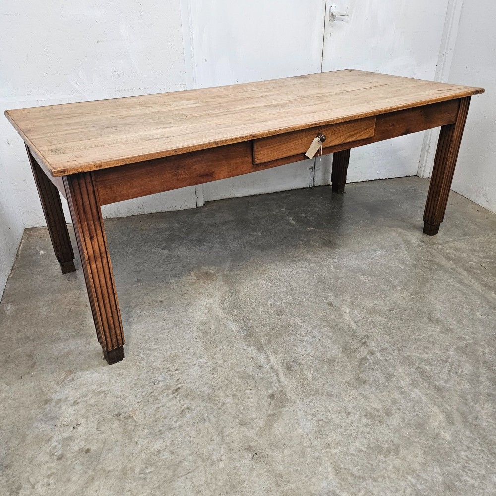 A rectangular French fruitwood dining table featuring a central frieze drawer with a wooden knob and fluted tapered legs. View IV