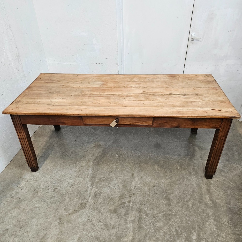 A rectangular French fruitwood dining table featuring a central frieze drawer with a wooden knob and fluted tapered legs. View VI
