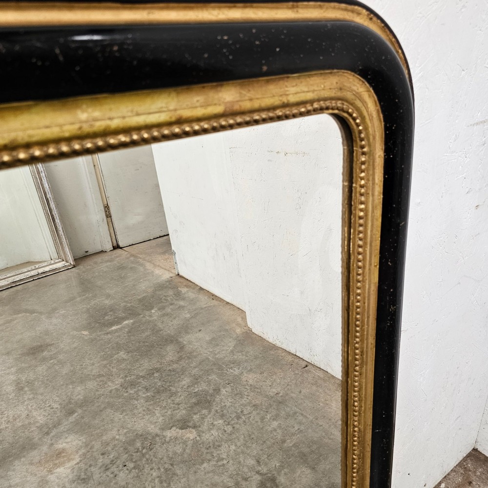 A rectangular French Louis Philippe mirror featuring rounded upper corners, an ebonised black outer frame, and a beaded gold leaf inner trim. View III
