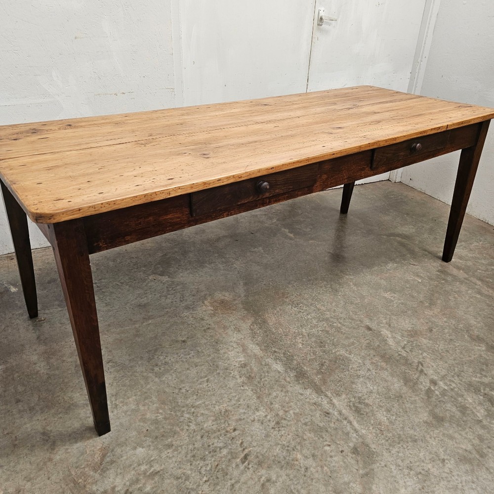 An antique French farmhouse dining table with a light pine plank top, two apron drawers, and a dark oak frame with tapered legs. View III
