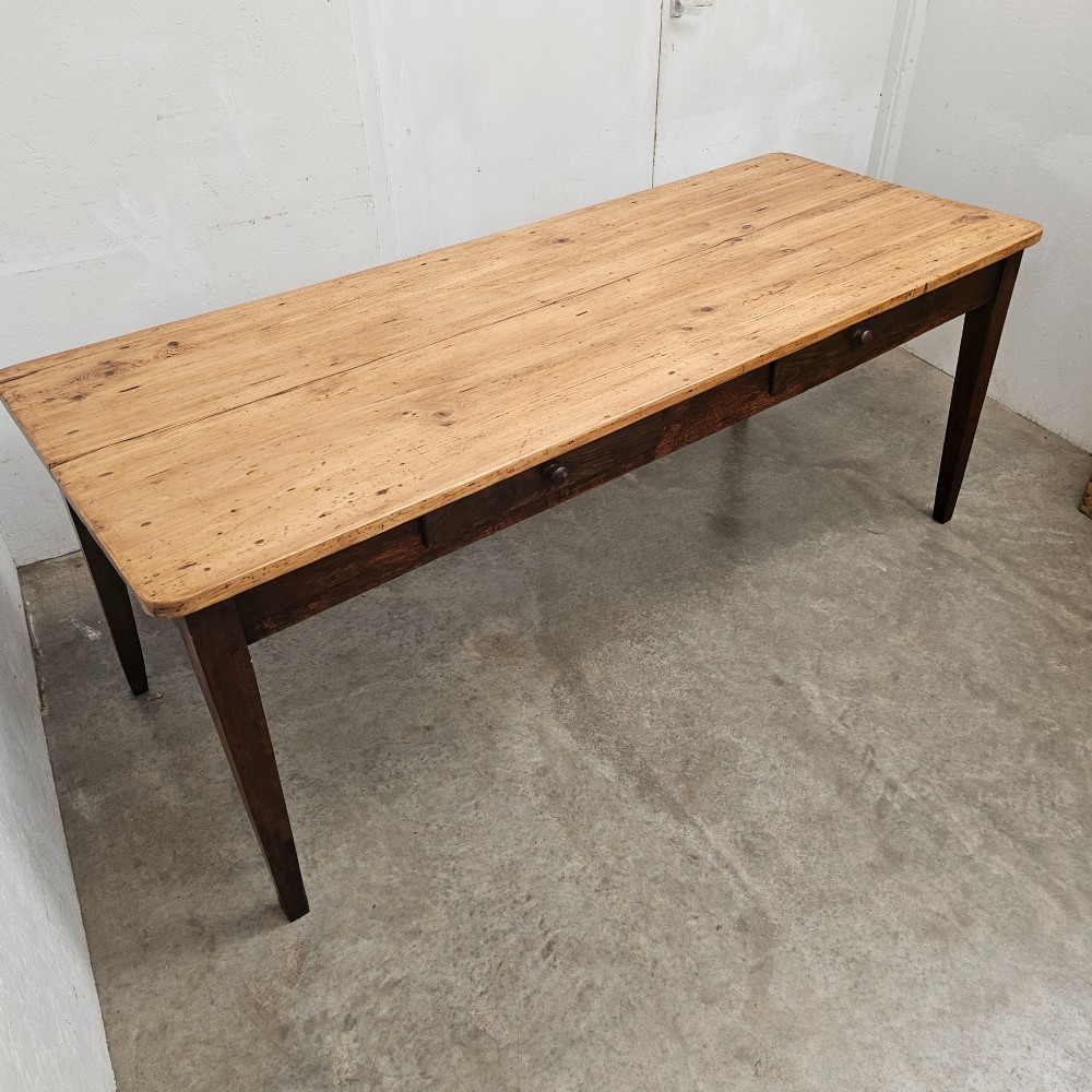 An antique French farmhouse dining table with a light pine plank top, two apron drawers, and a dark oak frame with tapered legs. View IV