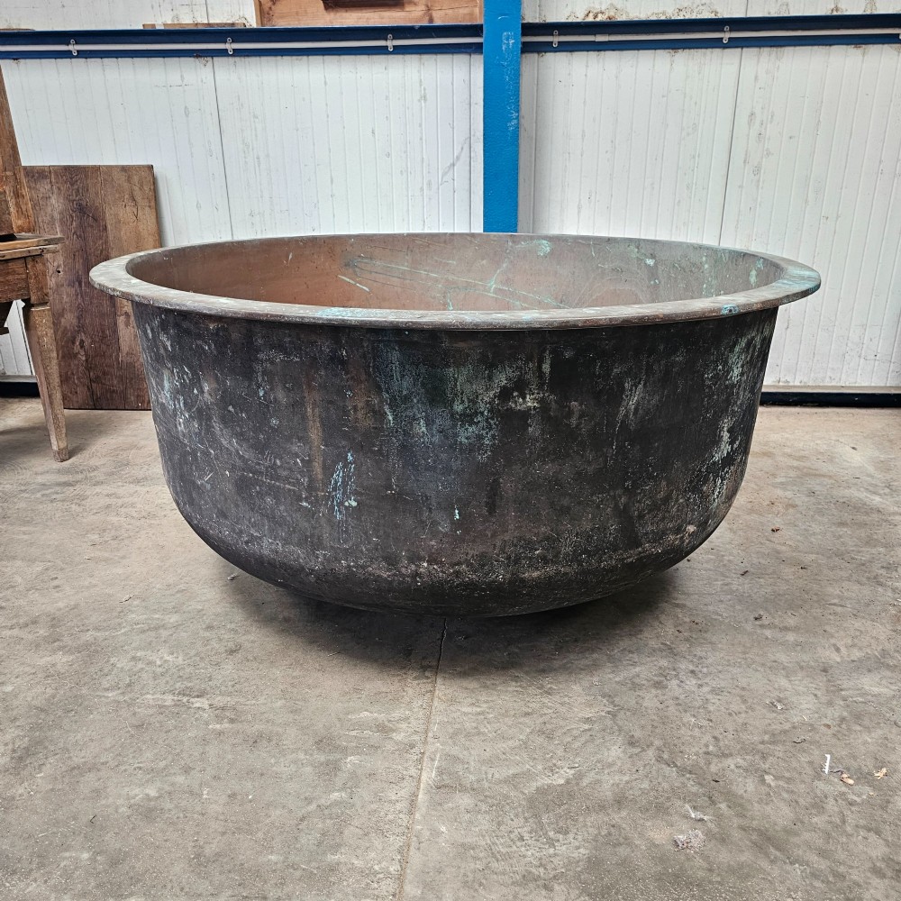 A massive antique French copper cheese vat with a reinforced rim, showing an oxidised exterior with verdigris green highlights.