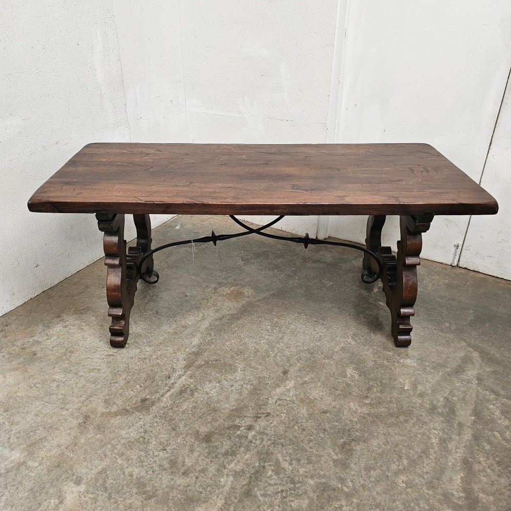 A dark brown rectangular wooden dining table with carved trestle legs connected by curved wrought iron stretchers. View IV