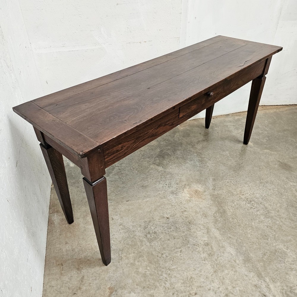 A rectangular dark oak console table featuring four square tapered legs, a single central drawer with a wooden knob, and a flat timber top. View VI