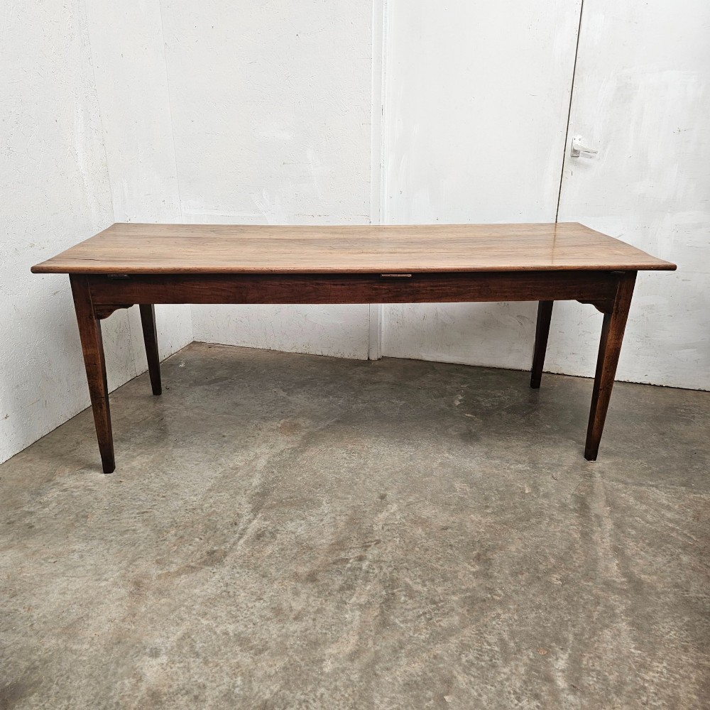 A rectangular French cherrywood farmhouse dining table featuring a plank top, simple apron, and four tapered square legs.