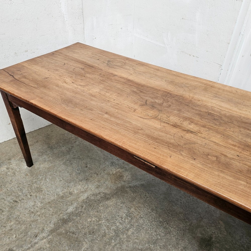 A rectangular French cherrywood farmhouse dining table featuring a plank top, simple apron, and four tapered square legs. View IV