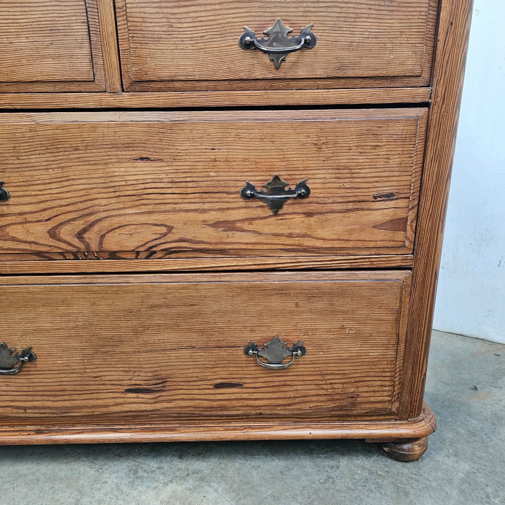 A Victorian pitch pine chest of drawers featuring a two-over-two drawer layout with brass drop handles and a visible wood grain. View II