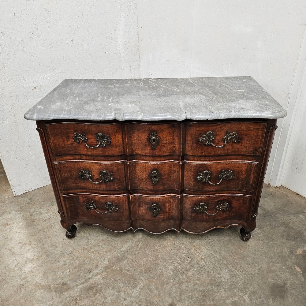 An 18th-century French provincial walnut commode with a shaped grey marble top, serpentine drawer fronts, bronze handles, and short cabriole legs. View V