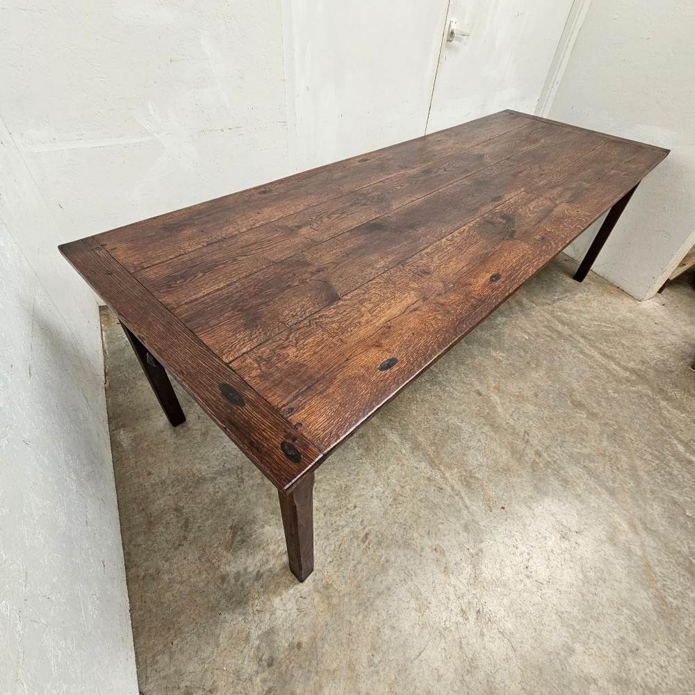 An eight-foot French oak farmhouse dining table with a dark patinated plank top, breadboard ends, and sturdy legs. View IV