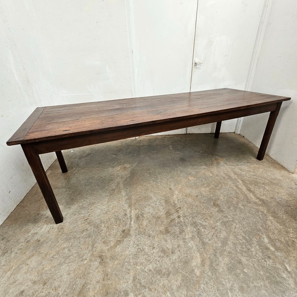 An eight-foot French oak farmhouse dining table with a dark patinated plank top, breadboard ends, and sturdy legs.