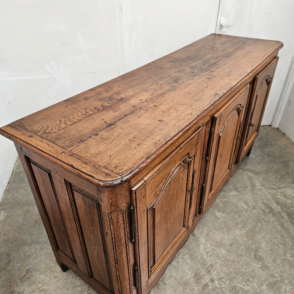 A French provincial oak enfilade featuring three arched panel doors, external iron hinges, and a scalloped lower apron. View II