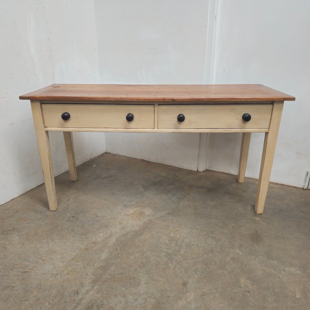 A nineteenth-century English painted pine dairy table with a natural timber top, a cream painted base, double drawers, and dark turned wooden knobs.