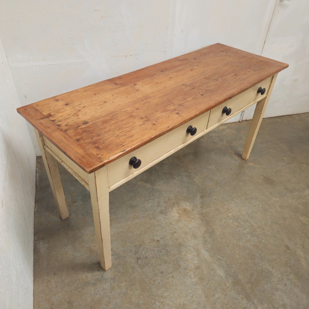 A nineteenth-century English painted pine dairy table with a natural timber top, a cream painted base, double drawers, and dark turned wooden knobs. View IV