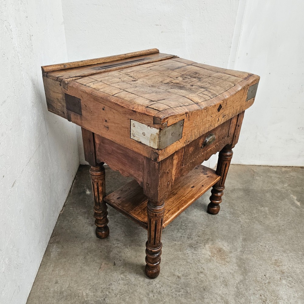A French beechwood butchers block featuring a thick end-grain top with metal corner brackets, a single drawer with a cup handle, a lower shelf, and turned legs. View III