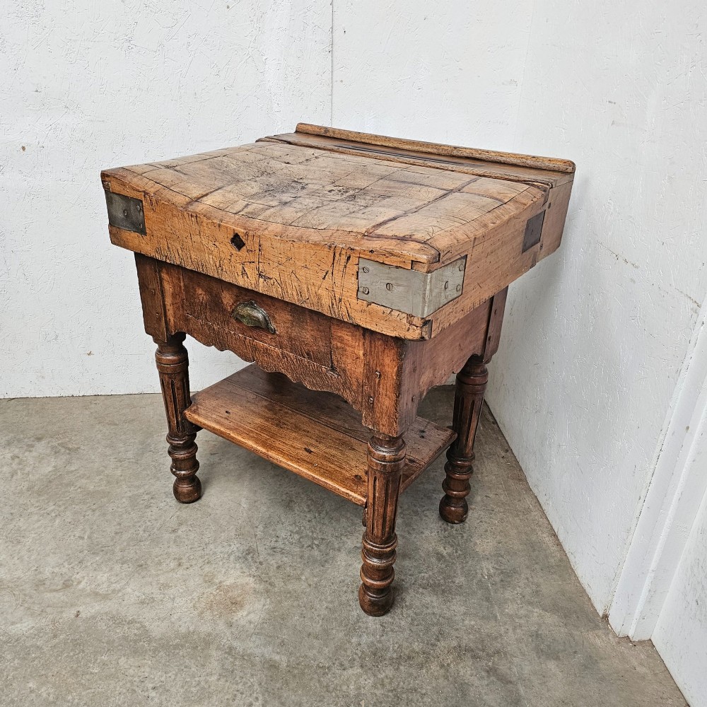 A French beechwood butchers block featuring a thick end-grain top with metal corner brackets, a single drawer with a cup handle, a lower shelf, and turned legs. View IV