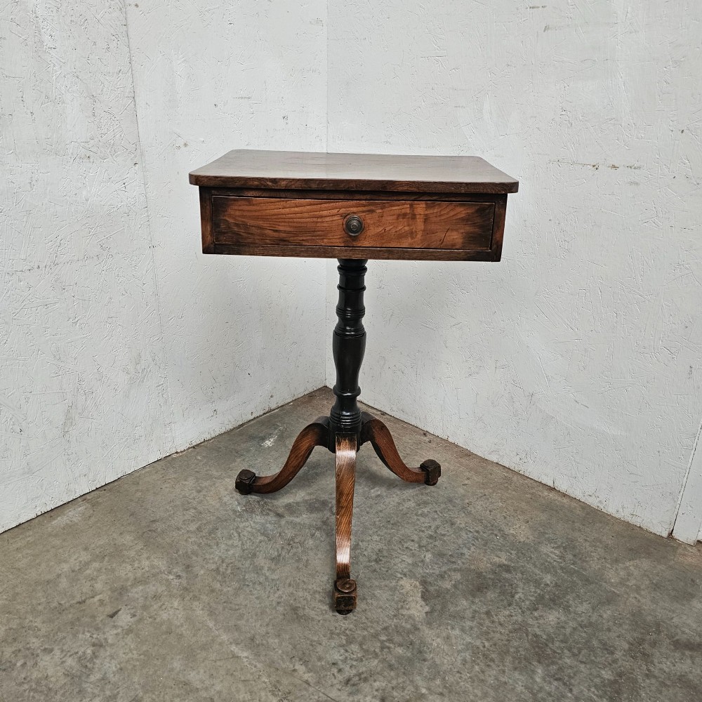 An antique elm pedestal side table featuring a single drawer with a round wooden knob, a turned central stem, and three curved tripod legs.