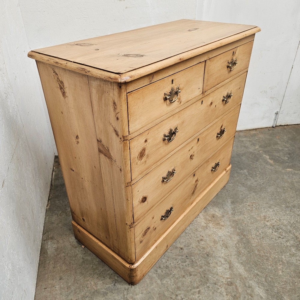 A Victorian light pine chest of drawers featuring a two-over-three drawer configuration, brass drop handles, keyholes, and a solid plinth base. View II