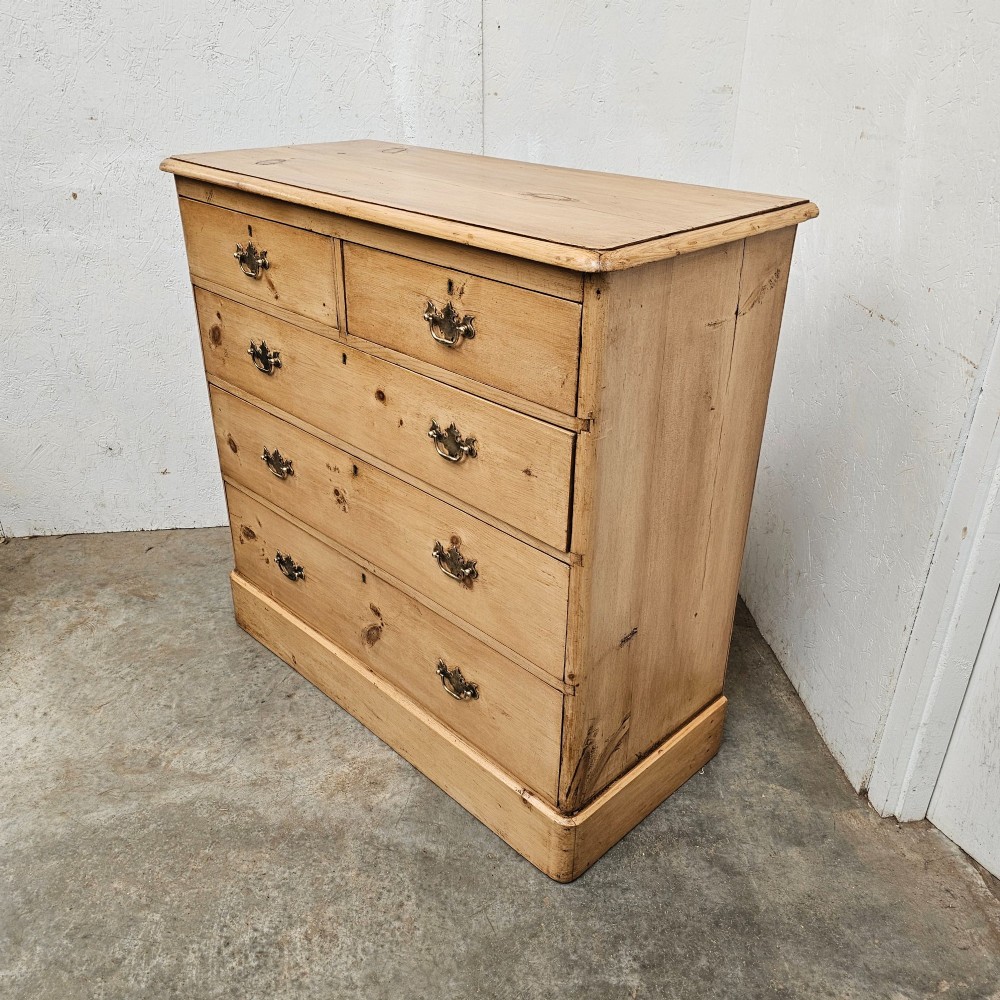 A Victorian light pine chest of drawers featuring a two-over-three drawer configuration, brass drop handles, keyholes, and a solid plinth base. View III