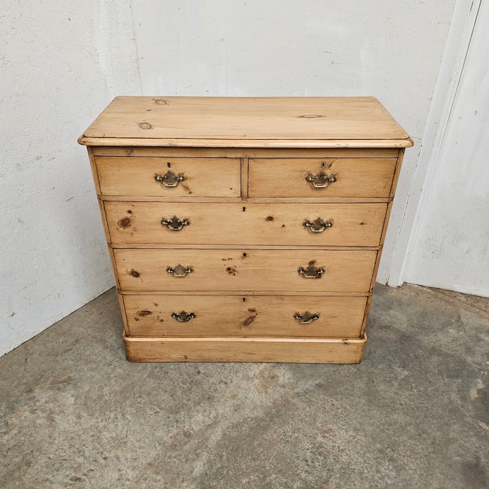 A Victorian light pine chest of drawers featuring a two-over-three drawer configuration, brass drop handles, keyholes, and a solid plinth base. View IV